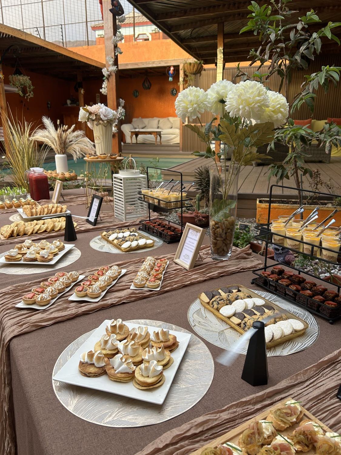 Mesa de banquetería Sweet Nice en una terraza de Iquique, con tartaletas, bocados y decoración de pampa